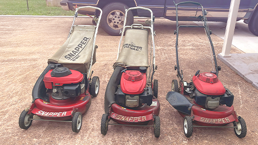 Three old Snapper push mowers lined up