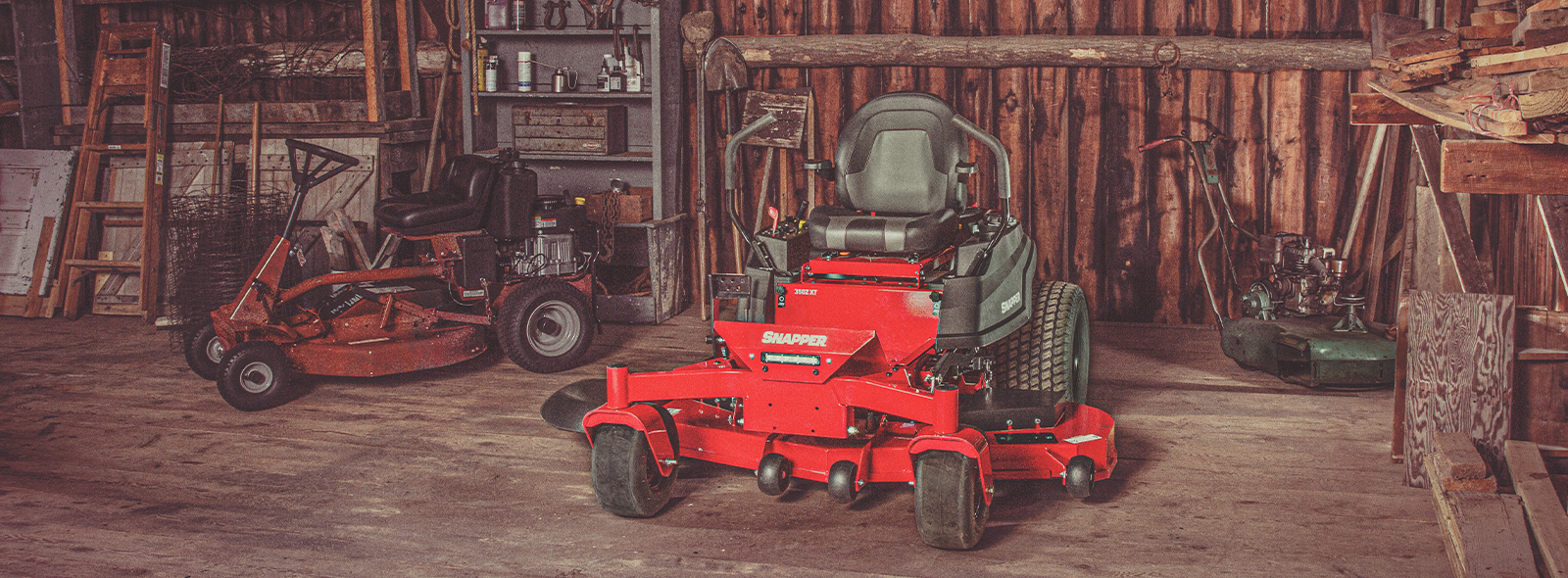 Snapper zero turn mower in garage with a Snapper rear engine rider showing in the background