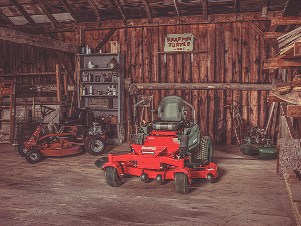 Snapper zero turn mower in garage with a Snapper rear engine rider showing in the background