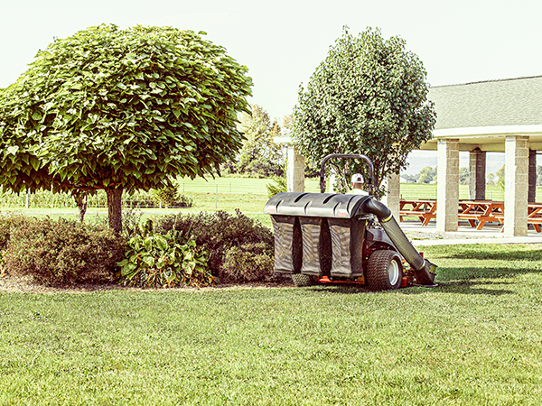 Person loading a bag of mulch on cargo bed zero turn mower attachment